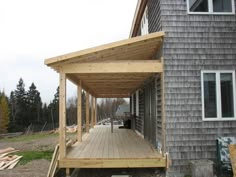 a house with a wooden deck and covered patio area in front of the house that is being built