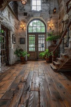 an old stone building with wood floors and windows on one side, potted plants in the other