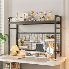 a desk with a computer on top of it next to a lamp and potted plant