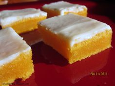 several pieces of yellow cake sitting on top of a red plate with white frosting