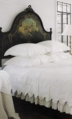 a bed with white linens and pillows in a bedroom next to two lamps on either side of the bed