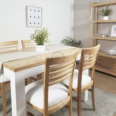 a dining room table with white chairs and a potted plant