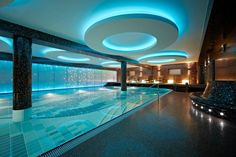 an indoor swimming pool with blue lights on the ceiling