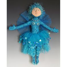 the doll is wearing a blue dress with feathers on it's head and arms