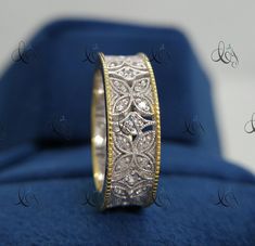 a wedding ring with two tone gold and diamond inlays on a blue velvet box