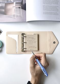 a person holding a pen and taking notes on a book with a clipboard attached to it