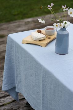 a blue vase with some white flowers in it and a wooden board on the table