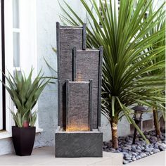 two tall water fountains sitting next to each other in front of a building with plants