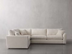 a white couch sitting on top of a gray floor next to a chair and ottoman