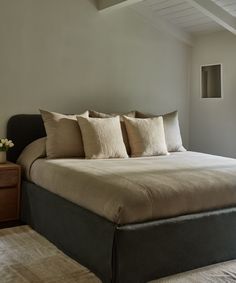 a large bed sitting in the middle of a bedroom next to a dresser and window