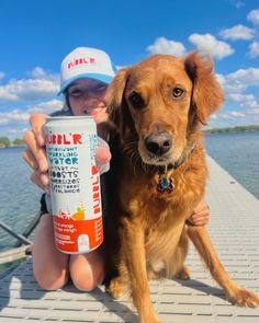 a dog is sitting next to a person holding a drink