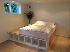 a bed sitting on top of a wooden floor next to a plant in a vase