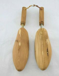 two wooden spoons hanging from hooks on a white surface with no one around them