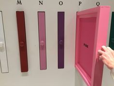 a person holding up a pink box in front of several different colored bars on the wall