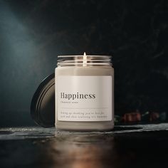 a candle sitting on top of a table with the words happiness written in white lettering