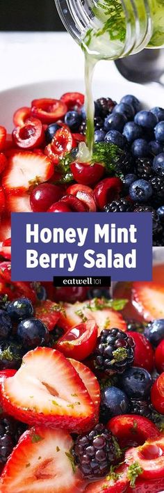 a bowl filled with berries and blueberries next to a bottle of honey mint berry salad