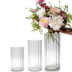 three vases with flowers and greenery in them, one is holding the other