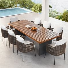 an outdoor dining table with white chairs and a bowl of fruit on the table next to it