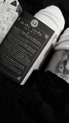 a person wearing white socks and holding a book in their hand with tattoos on it