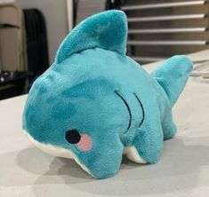 a blue stuffed shark laying on top of a table