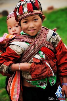 two young children are dressed in traditional clothing and holding each other while smiling for the camera