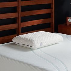 a close up of a mattress on a bed with wooden headboard and night stand