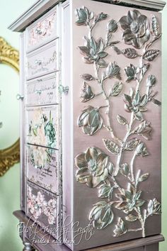 a silver cabinet with flowers painted on it