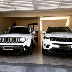 two white jeeps parked next to each other in a garage