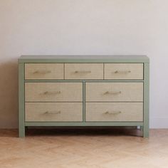 a green dresser sitting on top of a hard wood floor next to a white wall