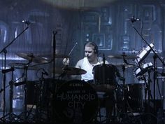 a man is playing drums on stage in front of other drummer's instruments and drum sticks