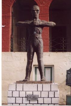 a statue of a man standing in front of a brick building