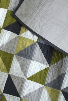 a green and white quilt on top of a bed