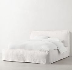 a bed with white sheets and pillows on it