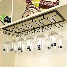 several wine glasses are hanging from a rack on the wall in front of a bicycle