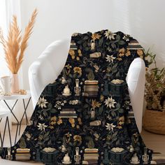 a black and gold blanket sitting on top of a white chair next to a plant