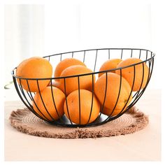 a wire basket filled with oranges on top of a table