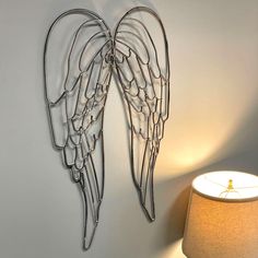 two metal angel wings on a wall next to a lamp