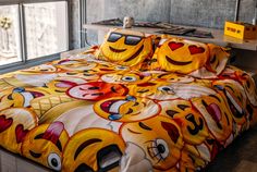 a bed covered in yellow and red smiley face sheets with pillows on top of it