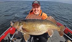 a man on a boat holding a large fish