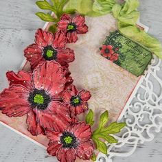 some red flowers are on top of a doily with green leaves and a tag