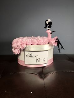 a cake that is sitting on top of a table with pink flowers in the shape of a woman's head