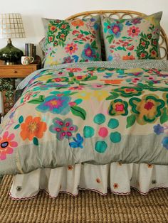 a bed with colorful flowers on it in a room next to a table and lamp