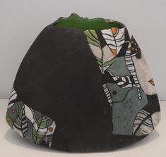 a black vase with green and white designs on it