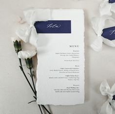 the menu is laid out next to some white flowers and paper with writing on it