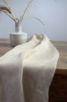 a vase with some plants in it sitting on a table next to a white cloth