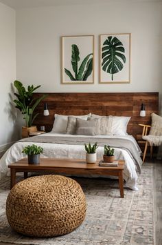 a large bed sitting next to two plants on top of a wooden table in a bedroom