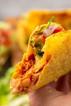 a hand holding a tortilla filled with meat and veggies