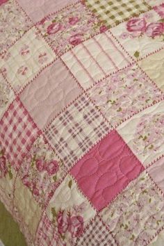 a pink and white checkered quilt on top of a bed with green trimmings