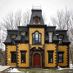 a yellow and black house with a red door