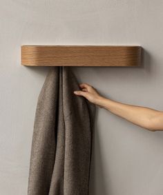 a person's hand is pulling up the edge of a towel rack on a wall